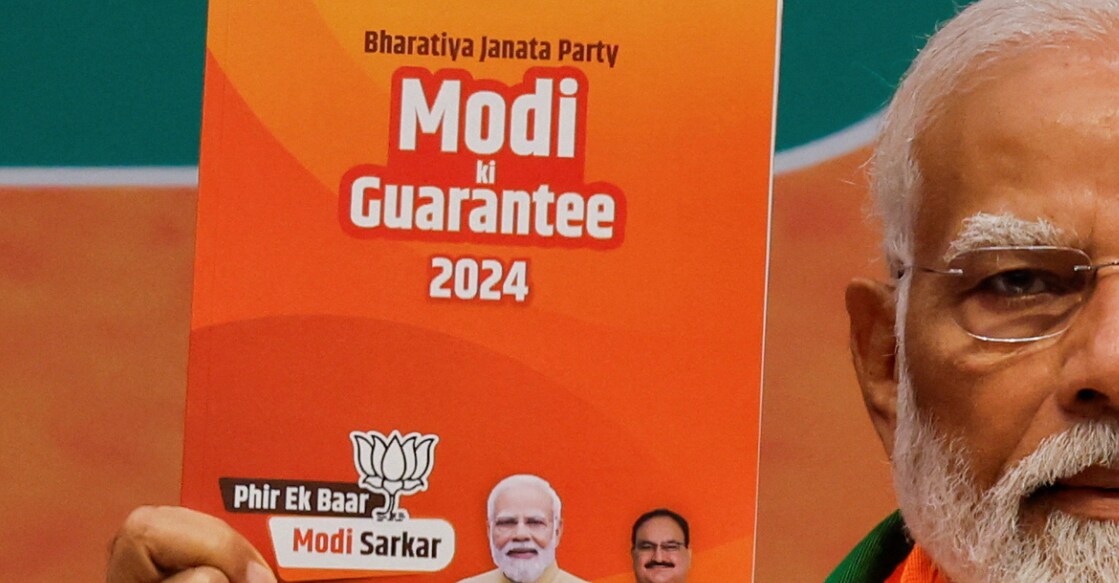 Prime Minister Narendra Modi displays a copy of the ruling Bharatiya Janata Party's (BJP) election manifesto for the general election, in New Delhi, India, April 14, 2024. Photo: PTI.