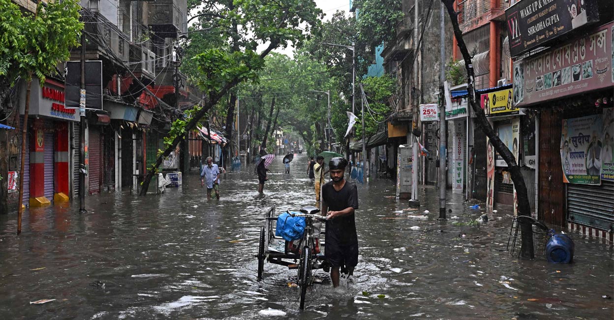 A man pushing a three-wheeler cart wades through a waterlogged street during rainfall in Kolkata on May 27, 2024, following the landfall of Cyclone Remal in India's West Bengal state. Photo: PTI. 