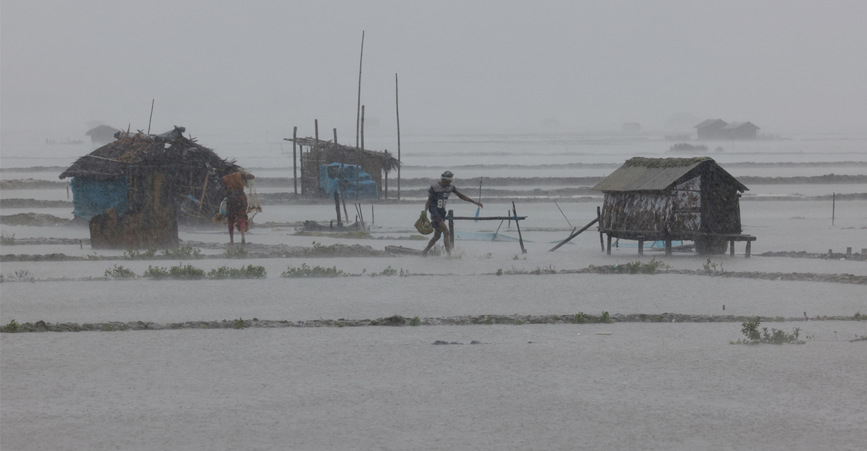 People walk along shrimp and crab farms that are flooded due to heavy rain as Cyclone Remal passes in Bangladesh. Photo: Reuters/Mohammad Ponir Hossain.