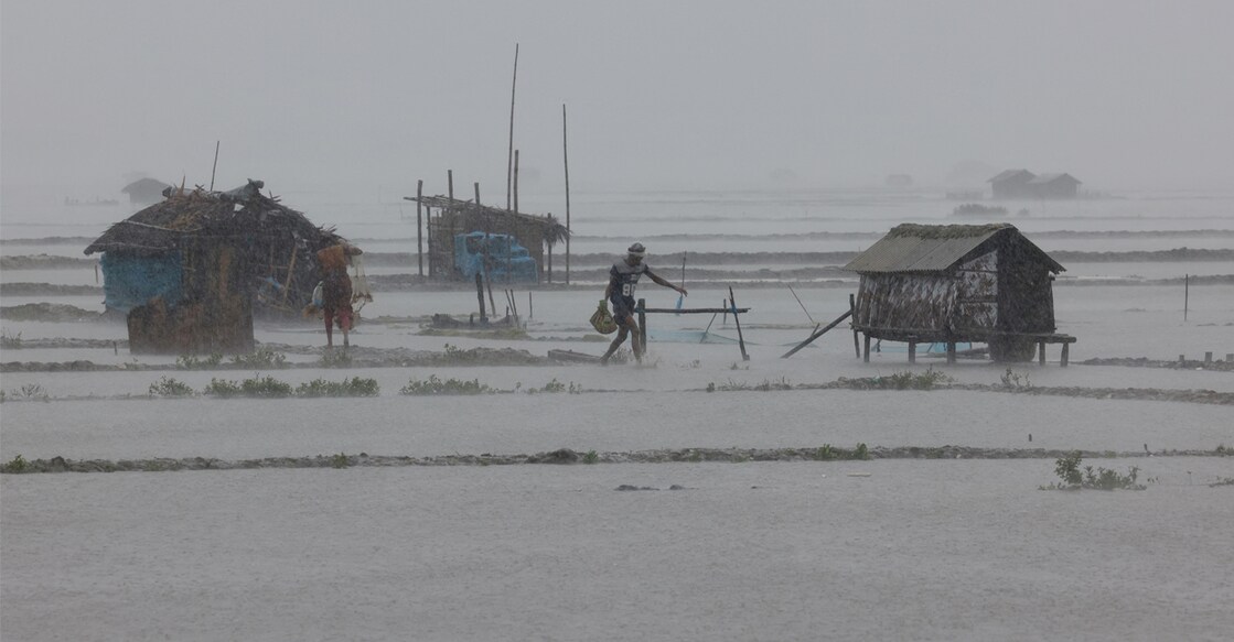 People walk along shrimp and crab farms that are flooded due to heavy rain as Cyclone Remal passes in Bangladesh. Photo: Reuters/Mohammad Ponir Hossain.