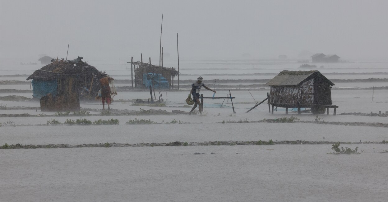 People walk along shrimp and crab farms that are flooded due to heavy rain as Cyclone Remal passes in Bangladesh. Photo: Reuters/Mohammad Ponir Hossain.