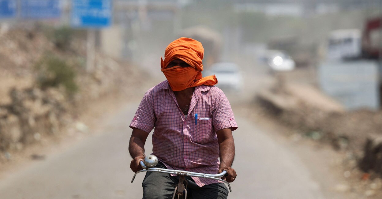 A man rides his cycle near a landfill site on a hot summer day during a heatwave in New Delhi on May 27, 2024. Photo: Reuters/Anushree Fadnavis