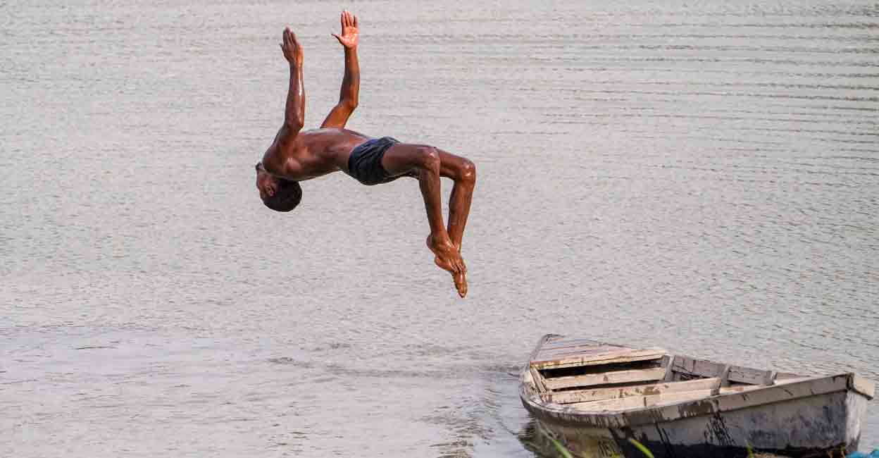 heatwave-delhi A boy jumps into a waterbody to get relief from the scorching heat on a hot summer day, in New Delhi, Tuesday, June 18, 2024. The India Meteorological Department (IMD) has issued a 'red' alert because of prevailing heatwave conditions in the national capital. Photo: PTI