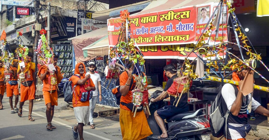 Kanwariyas walk past a shop on which banners with shopkeeper's name was put up on Kanwar Marg after an order issued by Uttar Pradesh Government, in Muzaffarnagar. Photo: PTI