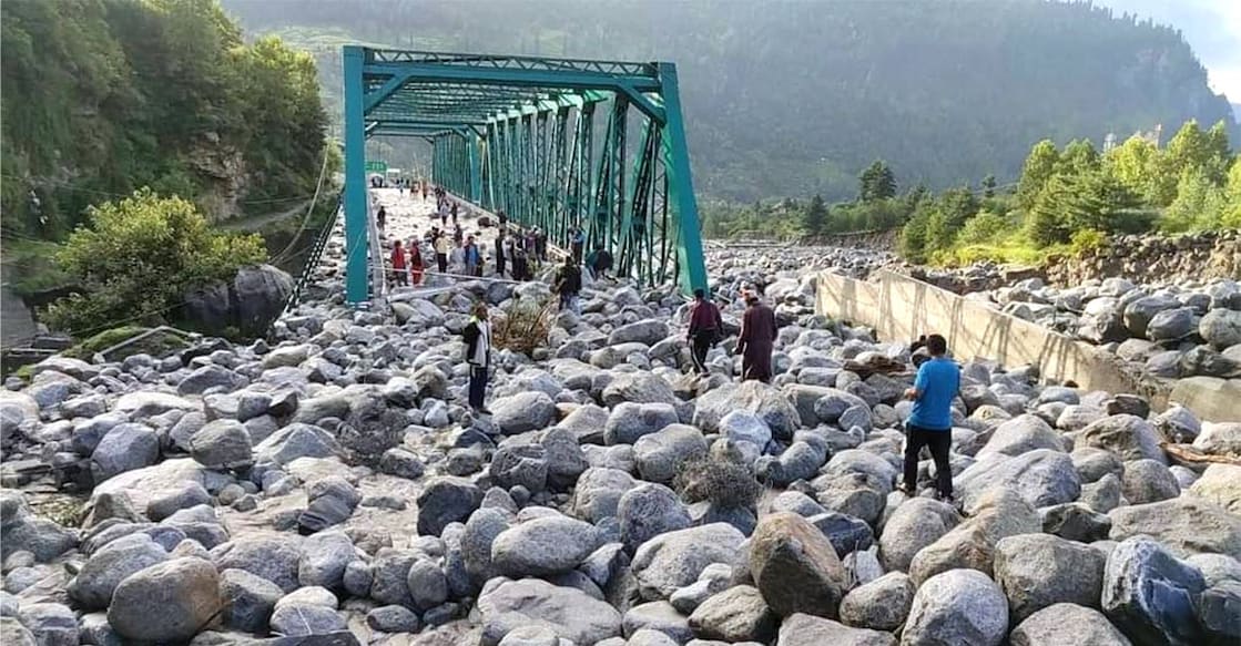 People stand near debris after flash floods triggered by cloud burst, near Manali, Thursday, July 25, 2024. Photo: PTI. 
