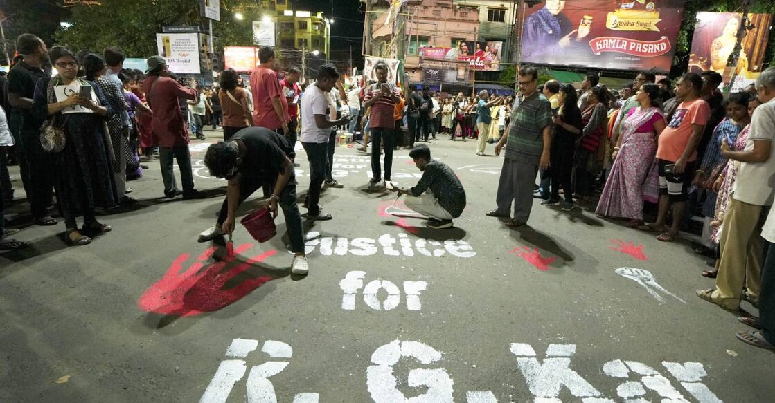 People paint slogans on a road during a protest over the alleged sexual assault and murder of a trainee doctor, in Kolkata. Photo: PTI