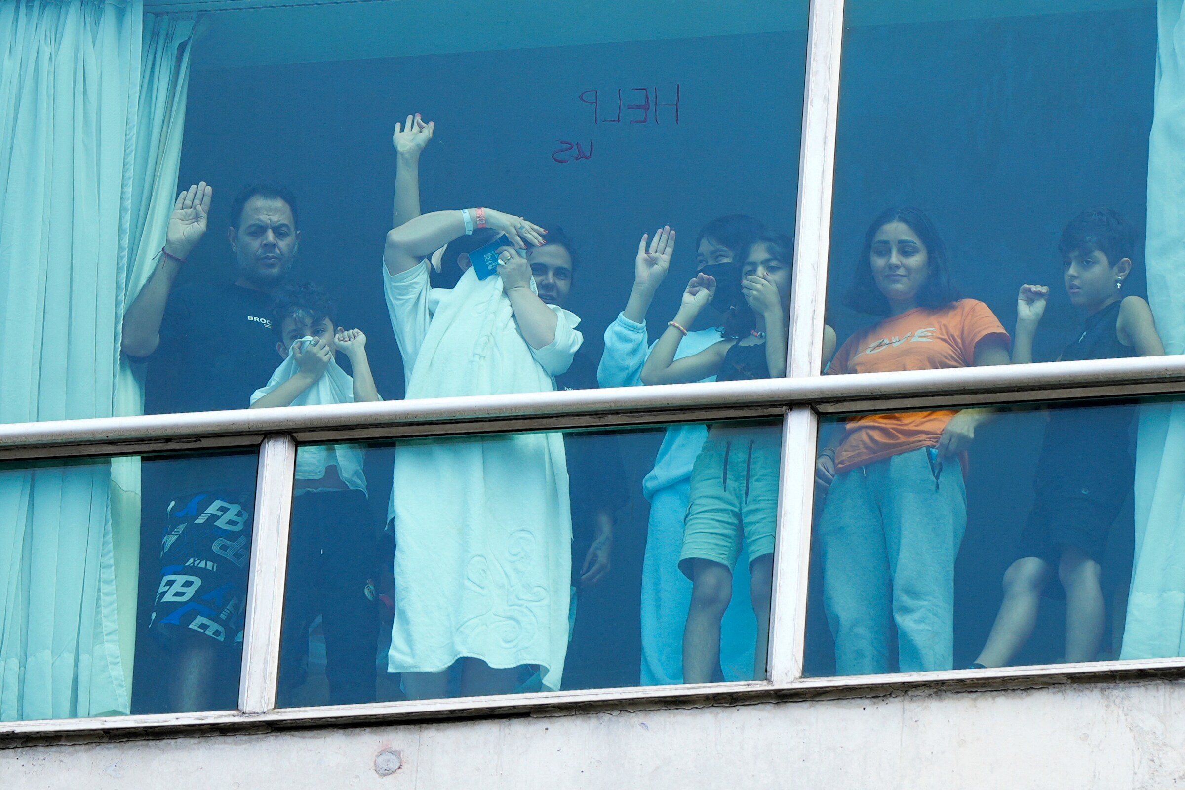 Migrants deported from the US gesture as they look out the window of the Decapolis Hotel, where they are temporarily staying in Panama City. Photo: ARNULFO FRANCO/AFP