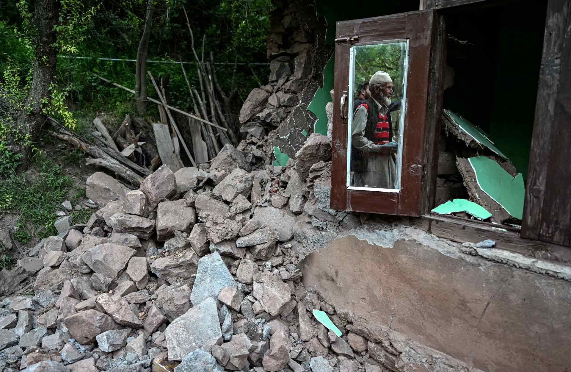 INDIA-PAKISTAN-KASHMIR-UNREST An elderly man is seen reflected on the window glass of a house damaged by Pakistani artillery shelling in Kalgi village in Uri, about 125kms from Srinagar, on May 8, 2025. Photo: AFP/Sajjad Hussain