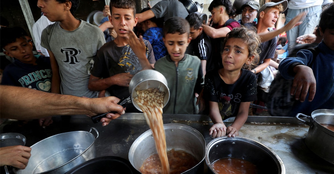 Palestinians wait to receive food cooked by a charity kitchen in Gaza City, May 21, 2025. REUTERS/Mahmoud Issa