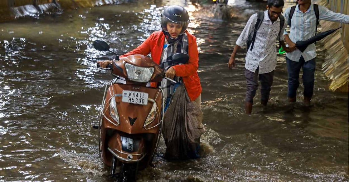 Bengaluru rain A woman struggles through a waterlogged street in Bengaluru. Photo: PTI