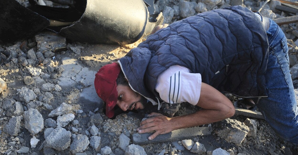 PALESTINIAN-ISRAEL-CONFLICT-STRIKES A man places his ears above debris of a destroyed building following Israeli air strikes on a neighbourhood in the al-Maghazi refugee camp in the central Gaza Strip on November 6, 2023, amid ongoing battles between Israel and the Palestinian Hamas movement. Photo: Reuters/Yasser Qudih