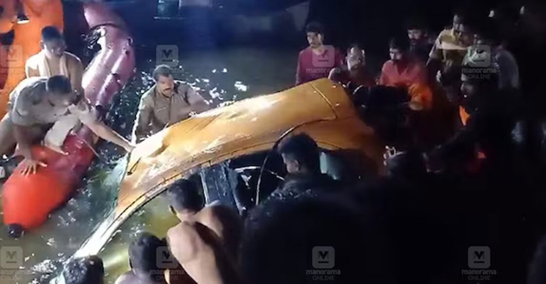 Fire & Rescue personnel and local people attempt to rescue people stranded inside the car that submerged in a water body at Kaipuzha Mutt on Cherthala-Kumarakom Road Monday night.
