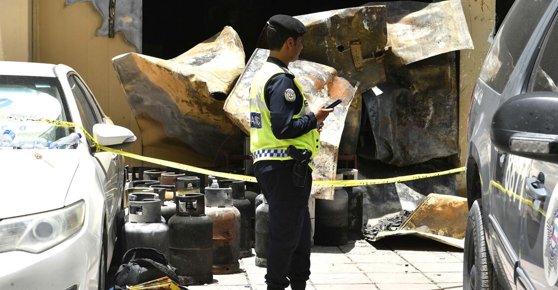 A policeman stands outisde the building in the Mangaf area of Kuwait that was gutted in fire. Gas cylinders that were possibly removed from the building can be seen. Photo: X/@kuna_ar
