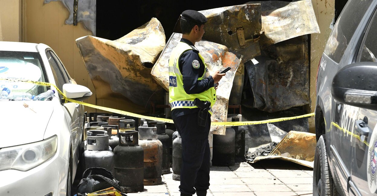 A policeman stands outisde the building in the Mangaf area of Kuwait that was gutted in fire. Gas cylinders that were possibly removed from the building can be seen. Photo: X/@kuna_ar
