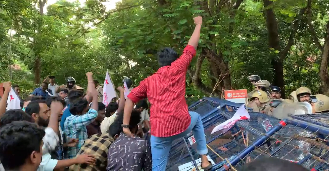 SFI activists drag down a barricade as policemen stand guard to the National Institute of Technology (NITC), Calicut on Friday. Photo: Screengrab/ Special arrangement