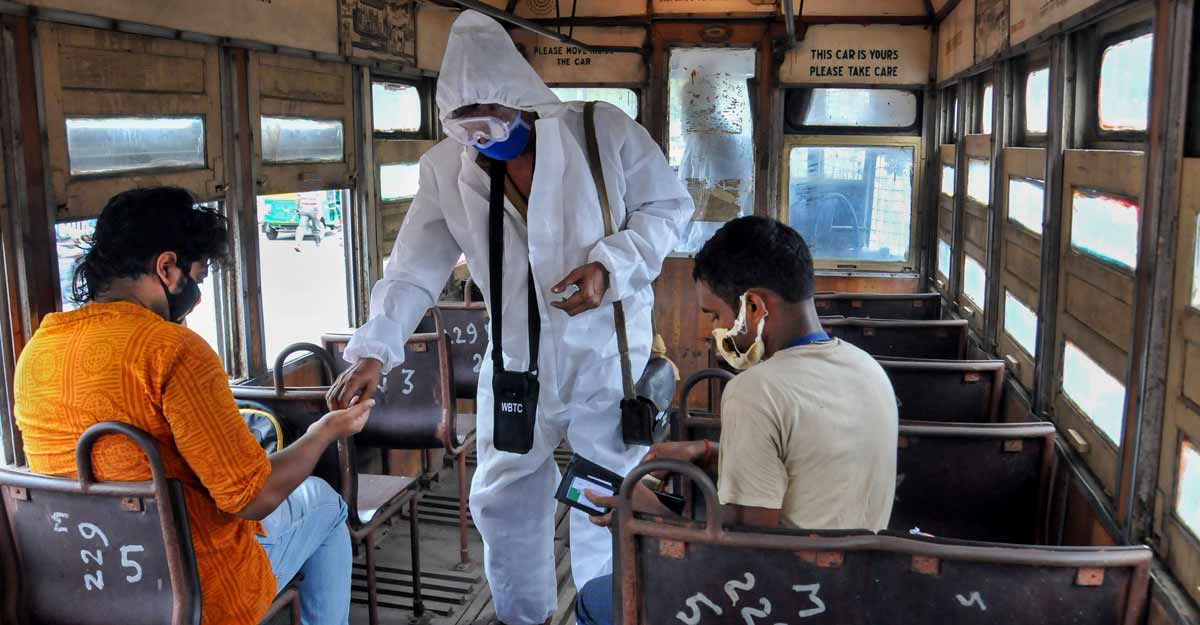 COVID-19 in India A tram conductor wearing a protective suit takes tickets from passengers after the authorities permitted to resume tram services with certain restrictions, during the fifth phase of COVID-19 nationwide lockdown, in Kolkata, Sunday. Photo: PTI