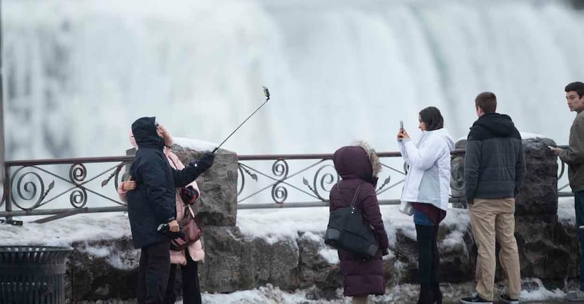 US-CANADA-WEATHER-STORM Tourists in Niagara Falls, Ontario, take photographs in front of the Horseshoe falls, January 9, 2018. A giant winter "bomb cyclone" walloped the US East Coast on January 5, 2018, with heavy snow and freezing cold that made for treacherous travel conditions and bone-chilling misery. (Photo by Geoff Robins / AFP)