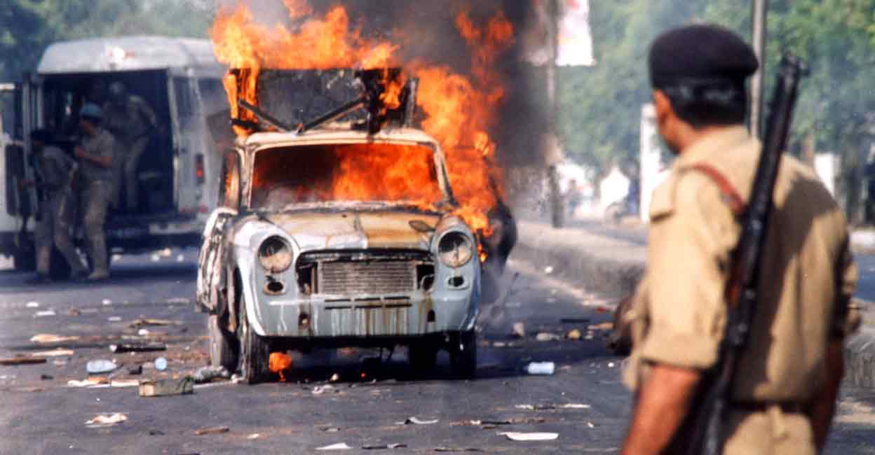 INDIA RELIGIOUS STRIFE A policeman watches a burning car in the Shahalam Tolnaka area of Ahmedabad in May, 2002. Photo: AP