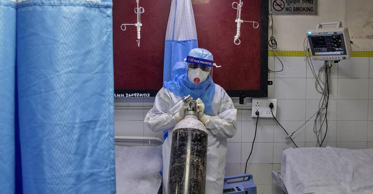 FILE PHOTO:  A medical worker wearing personal protective equipment (PPE) pushes an oxygen cylinder for a patient suffering from the coronavirus disease (COVID-19) at the casualty ward in Lok Nayak Jai Prakash (LNJP) hospital, in New Delhi, India July 17, 2020. REUTERS/Danish Siddiqui/File photo