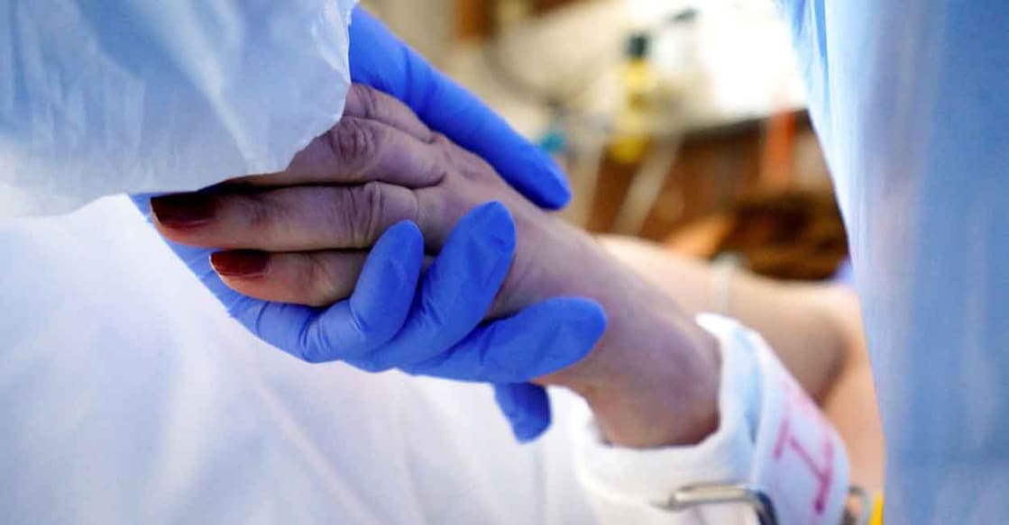 A medical specialist holds the hand of a patient suffering from the coronavirus disease (COVID-19) at the intensive care unit (ICU) of Toxicology and Sepsis clinic of the Riga East Clinical University Hospital in Riga, Latvia. Picture taken on October 29, 2021. Photo: Reuters/Janis Laizans