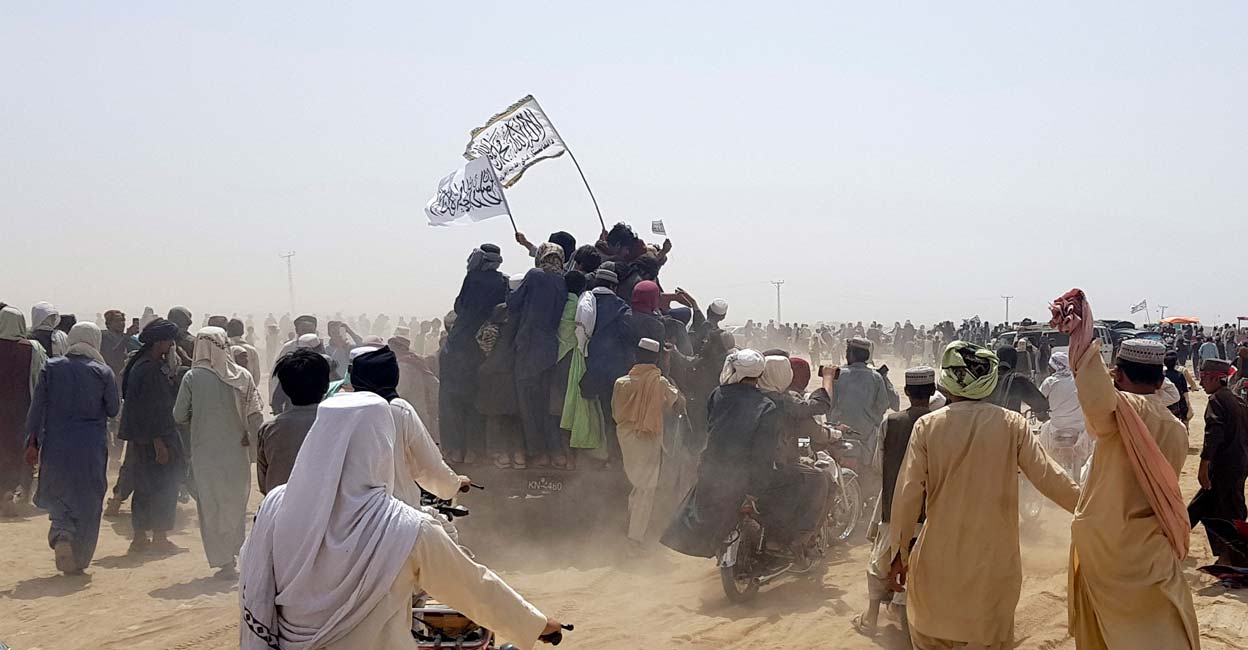 Pakistan-Afghanistan border town of Chaman People standing on a vehicle hold Taliban flags as people gather near the Friendship Gate crossing point in the Pakistan-Afghanistan border town of Chaman, Pakistan July 14, 2021. Picture taken July 14, 2021. Photo: REUTERS/Abdul Khaliq Achakzai