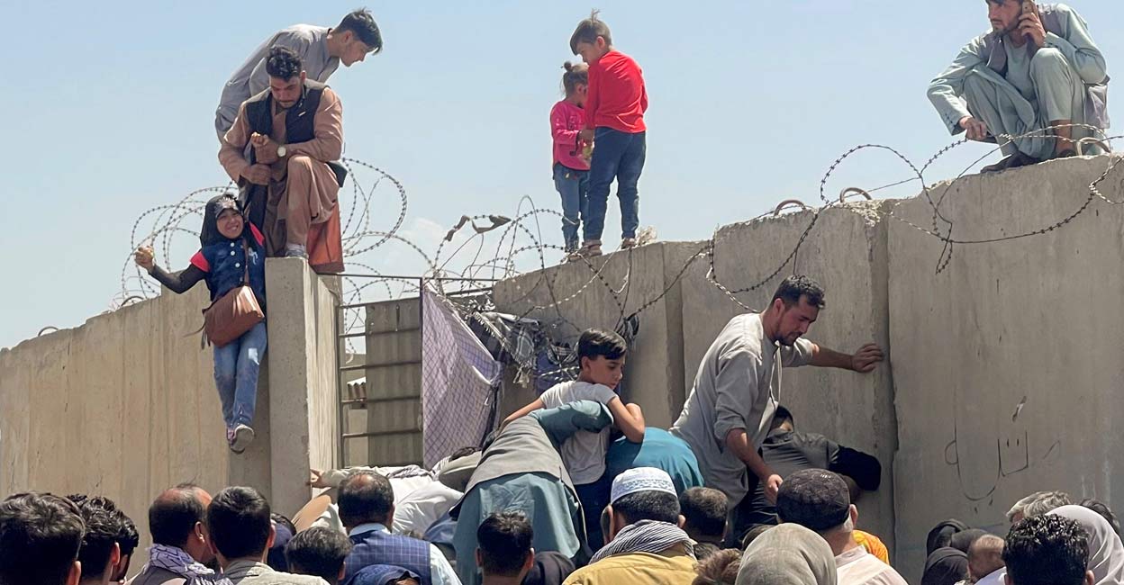 AFGHANISTAN-CONFLICT A man pulls a girl to get inside Hamid Karzai International Airport in Kabul, Afghanistan August 16, 2021. Photo: REUTERS/Stringer