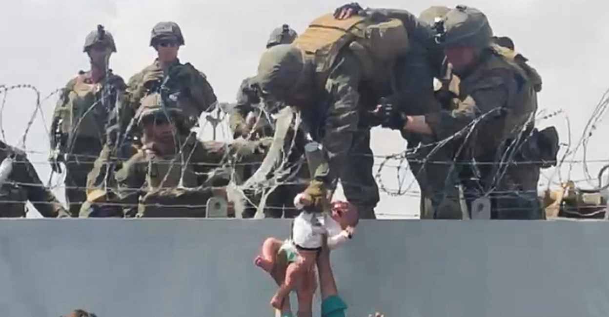 A baby is handed over to the American army over the perimeter wall of the airport for it to be evacuated, in Kabul, Afghanistan, August 19, 2021. Omar Haidari/Reuters