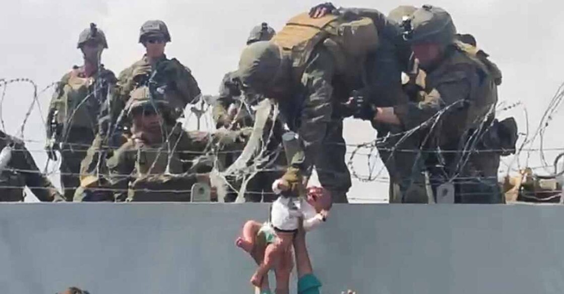 West struggles with Afghanistan chaos, Biden again defends withdrawal A baby is handed over to the American army over the perimeter wall of the airport for it to be evacuated, in Kabul, Afghanistan, August 19, 2021. Omar Haidari/Reuters