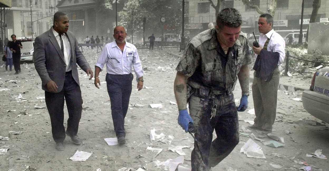 A police officer and other people walking a few blocks from the World Trade Center site in New York streets covered with debris. A police officer and other people walking a few blocks from the World Trade Center site in New York streets covered with debris. AFP PHOTO / STAN HONDA