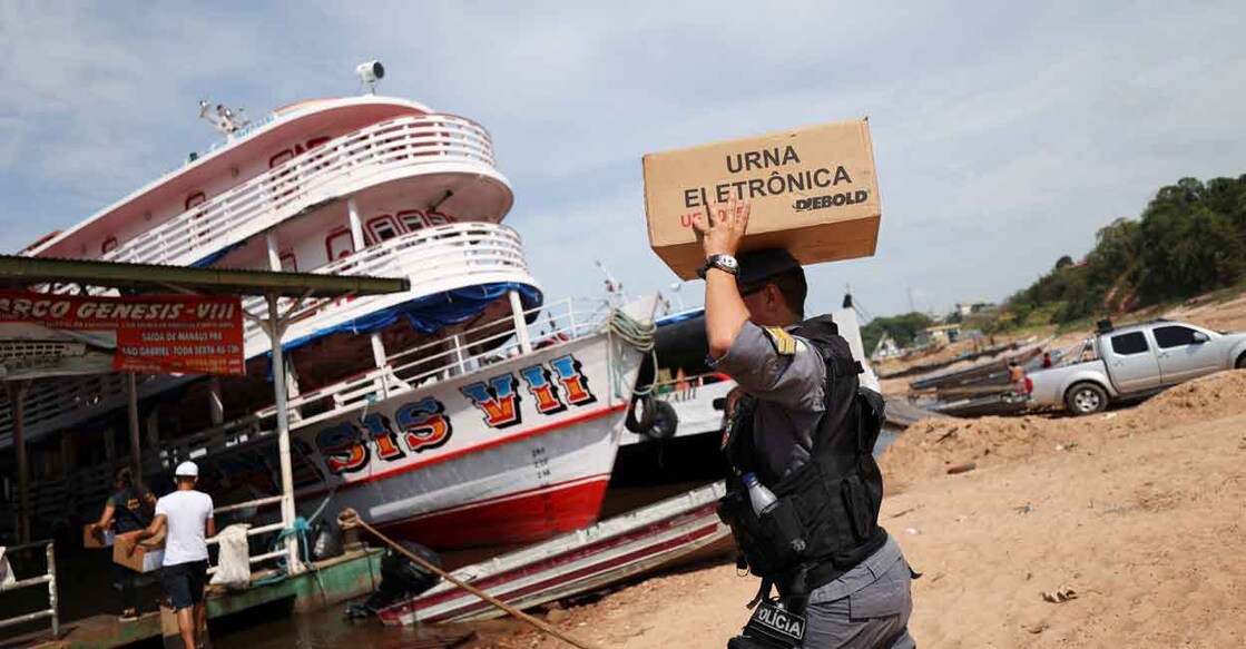 A police officer carries an electronic ballot box to voting polling stations of a community of "ribeirinhos" (forest dwellers), ahead of Brazilian elections, in Sao Raimundo Port, in Manaus, Brazil October 29, 2022. REUTERS/Bruno Kelly