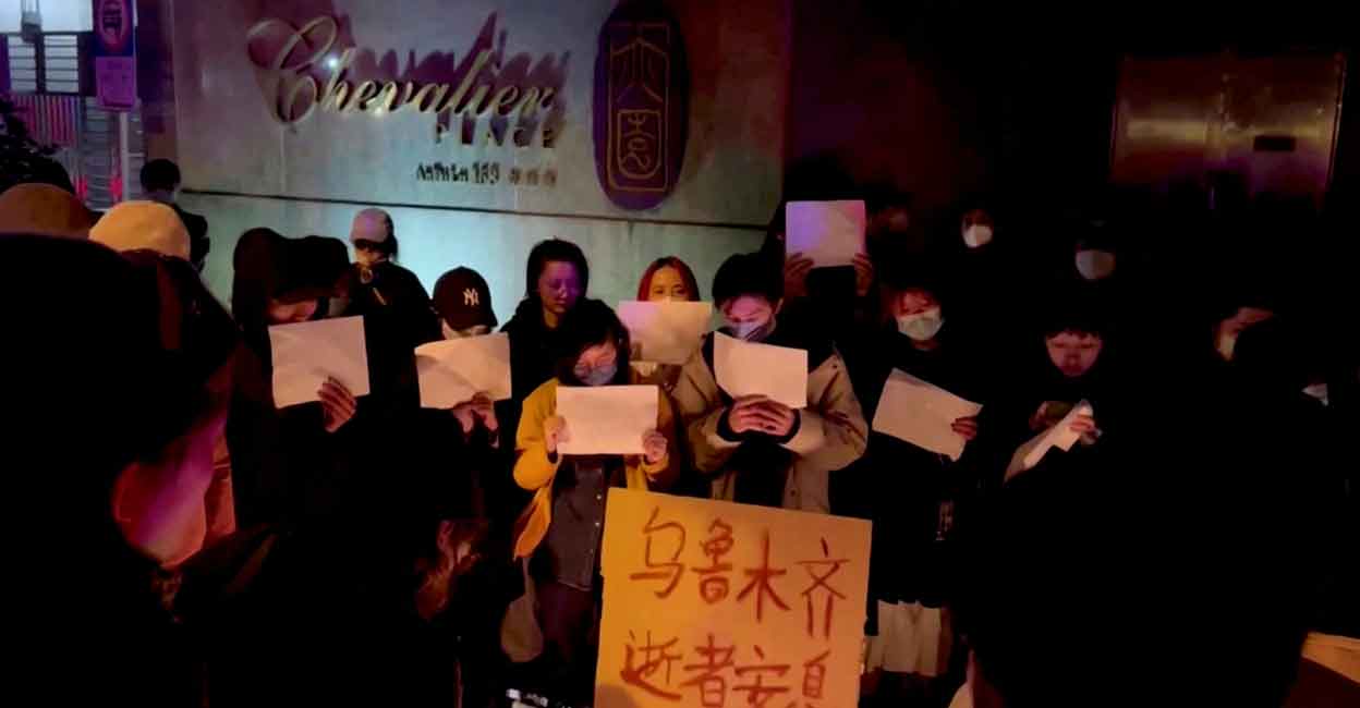 People hold signs during a candlelight vigil held for the victims of the Urumqi fire, in Shanghai, China November 26, 2022 in this picture obtained from a social media video. Photo: Gao Ming/via REUTERS