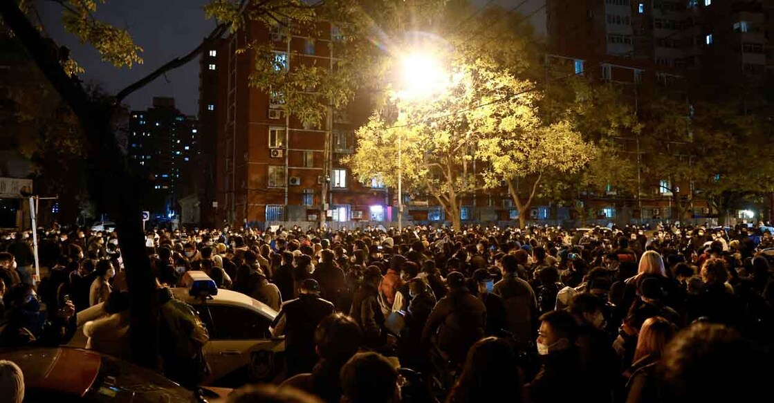 People gather for a vigil and hold white sheets of paper in protest of coronavirus disease restrictions, as they commemorate the victims of a fire in Urumqi, as outbreaks of the coronavirus disease continue in Beijing. Photo: REUTERS/Thomas Peter