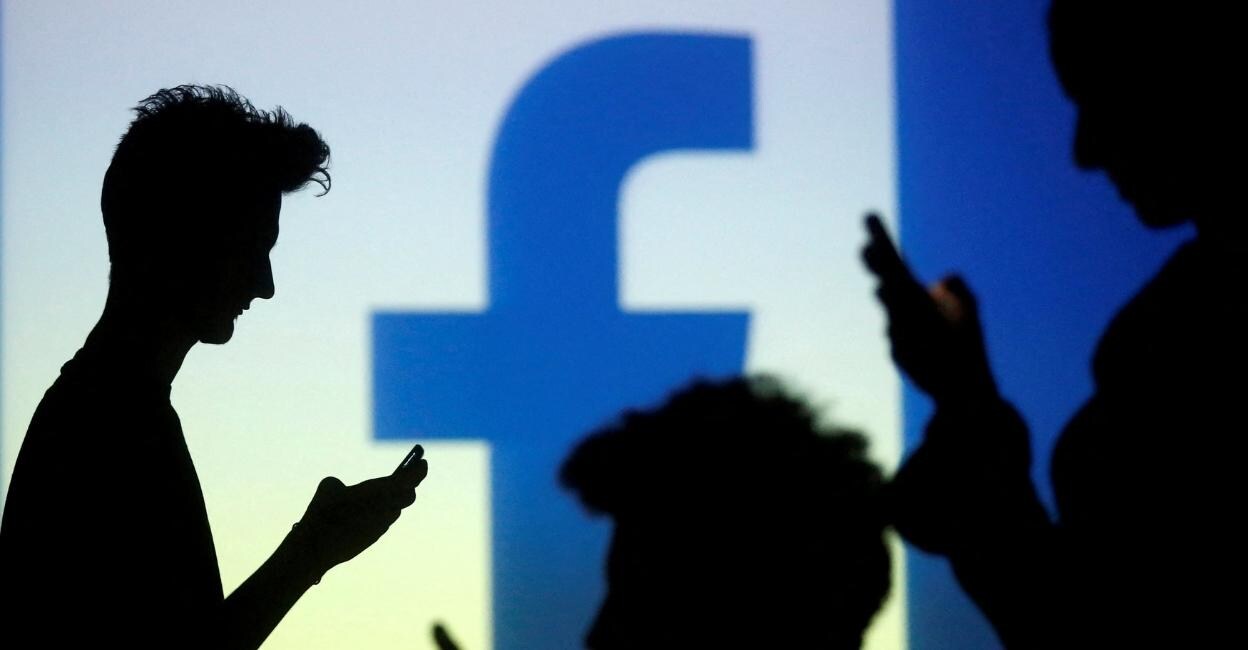 People are silhouetted as they pose with mobile devices in front of a screen projected with a Facebook logo, in this picture illustration taken in Zenica, October 29, 2014. File Photo: Reuters