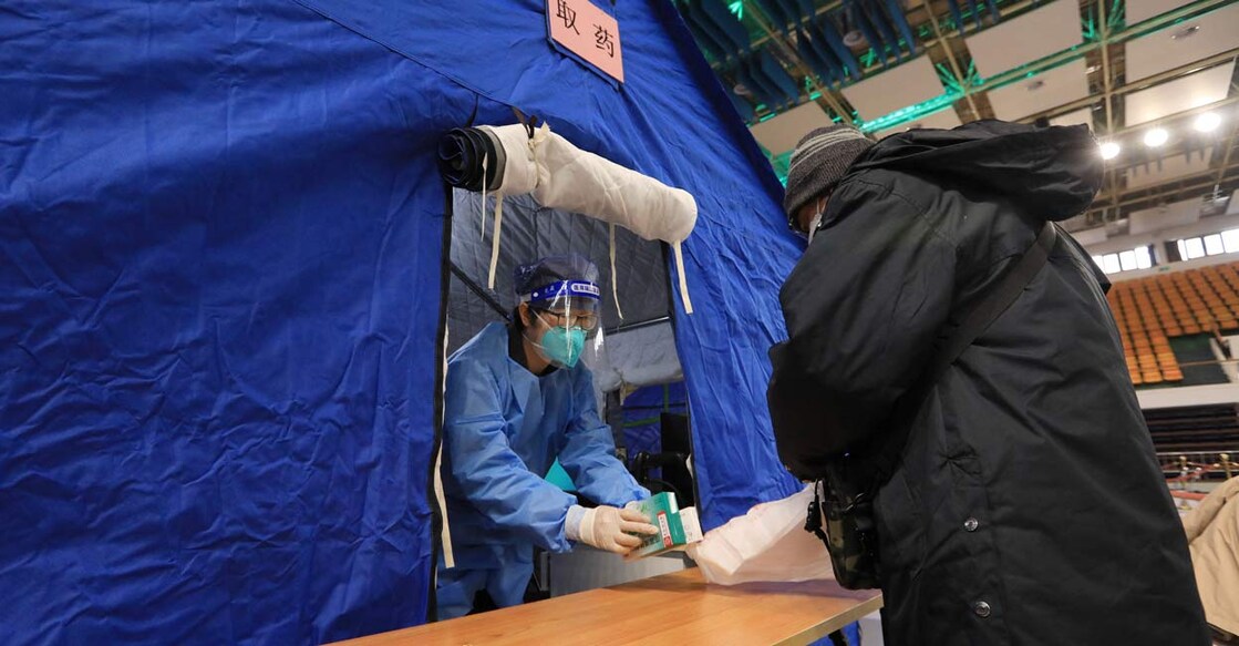 A medical worker hands fever medicine to a resident at a makeshift fever clinic set up inside a stadium, amid the coronavirus disease (COVID-19) outbreak in Beijing, China : China Daily via REUTERS