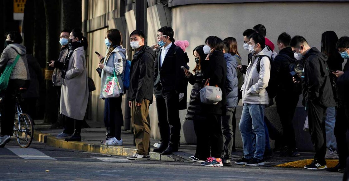 People wearing face masks wait at a traffic light to cross a street, as coronavirus disease (COVID-19) outbreaks continue in Shanghai, China: REUTERS/Aly Song