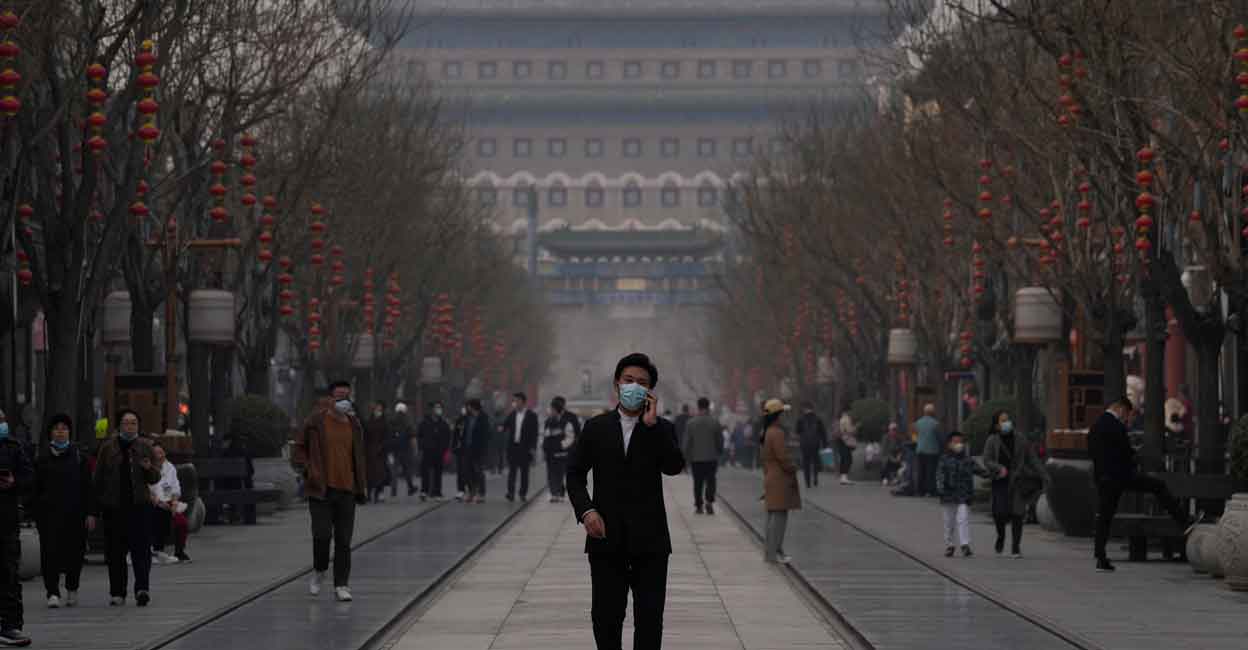 Virus Outbreak China Hong Kong A man wearing a mask walks down the Qianmen Ave retail street on Thursday, March 10, 2022, in Beijing. China is tackling a COVID-19 spike with selective lockdowns and other measures that appear to slightly ease its draconian "zero tolerance" strategy. (AP Photo/Ng Han Guan)