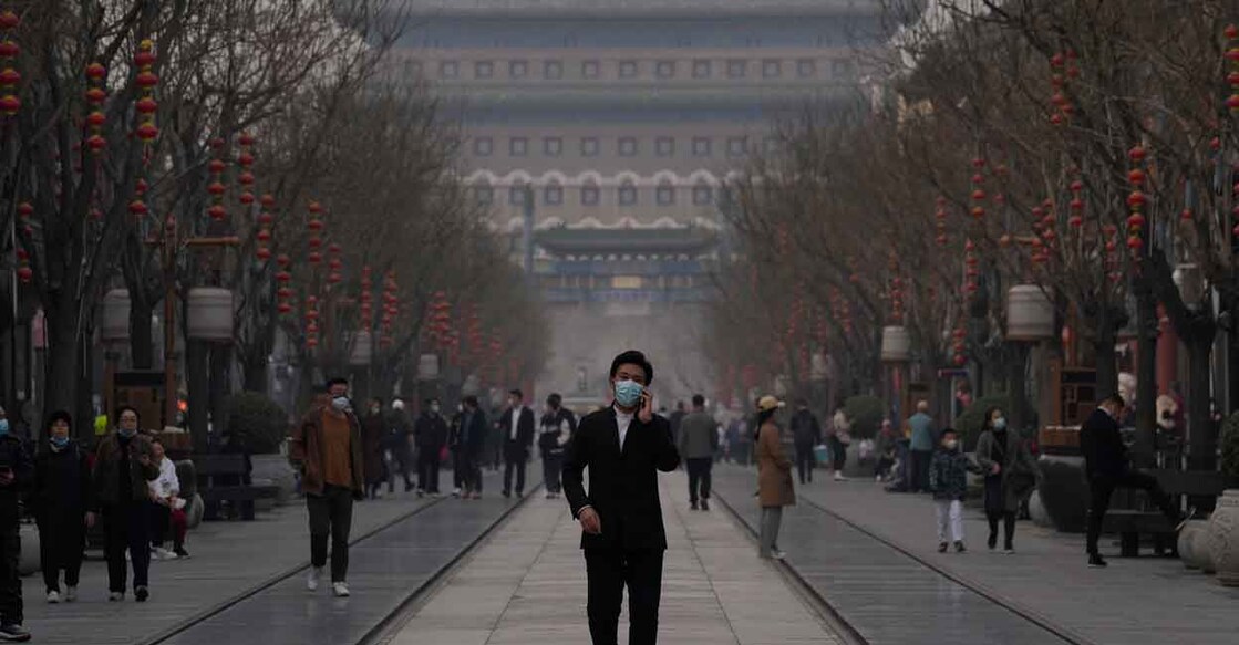 A man wearing a mask walks down the Qianmen Ave retail street on Thursday, March 10, 2022, in Beijing. China is tackling a COVID-19 spike with selective lockdowns and other measures that appear to slightly ease its draconian "zero tolerance" strategy. (AP Photo/Ng Han Guan)