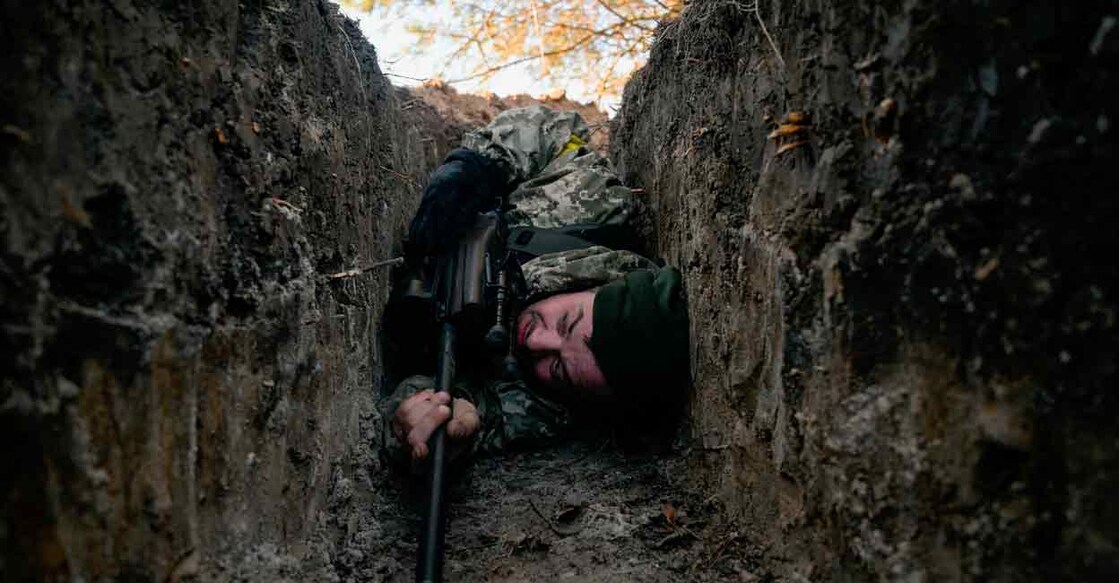 A Ukrainian soldier hides from a helicopter airstrike amid Russia's invasion of Ukraine, near Demydiv. Reuters