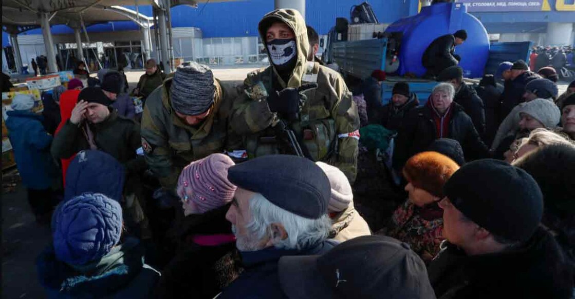 Service members of pro-Russian troops stand guard as people queue to receive humanitarian aid near a damaged store of wholesaler Metro in the course of Ukraine-Russia conflict in the besieged southern port city of Mariupol, Ukraine on Thursday. Photo: Reuters