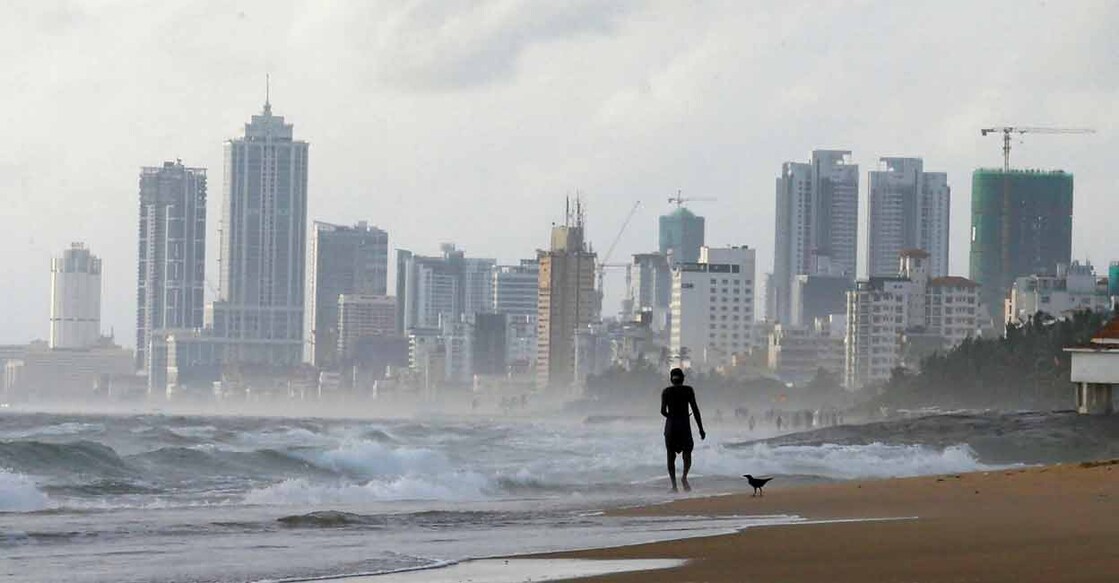 FILE PHOTO: A man walks along a beach, against the backdrop of Colombo's Financial City, Sri Lanka June 12, 2018. REUTERS/ Dinuka Liyanawatte