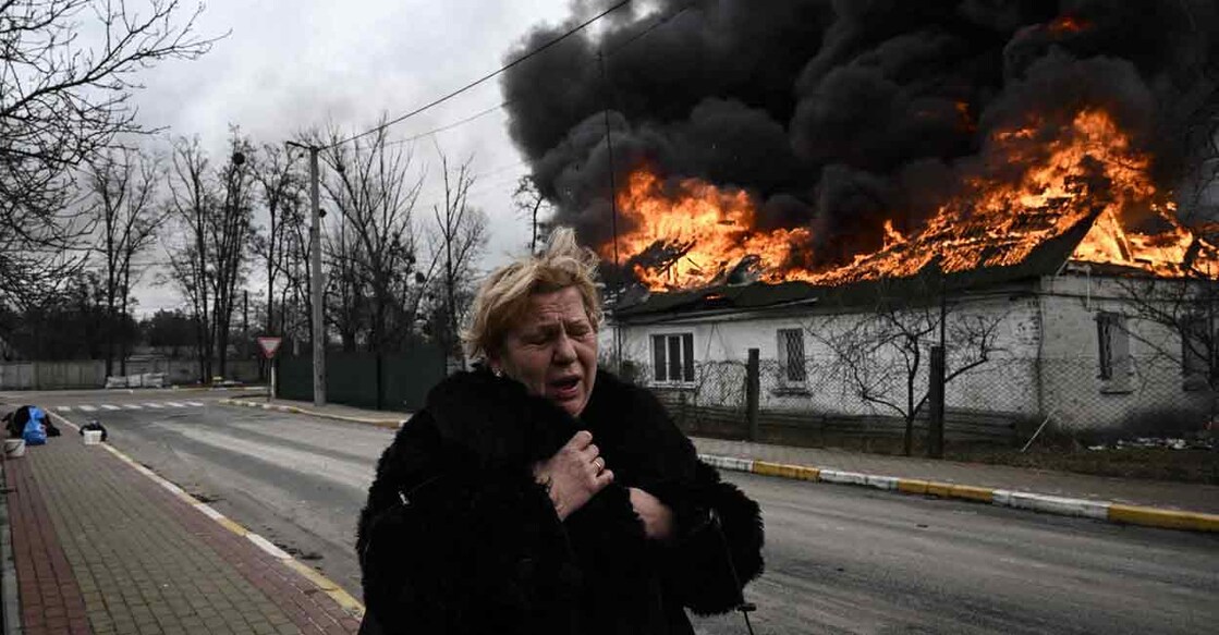 A woman reacts as she stands in front of a house burning after being shelled in the city of Irpin, outside Kyiv, Ukraine on Friday. Photo: AFP