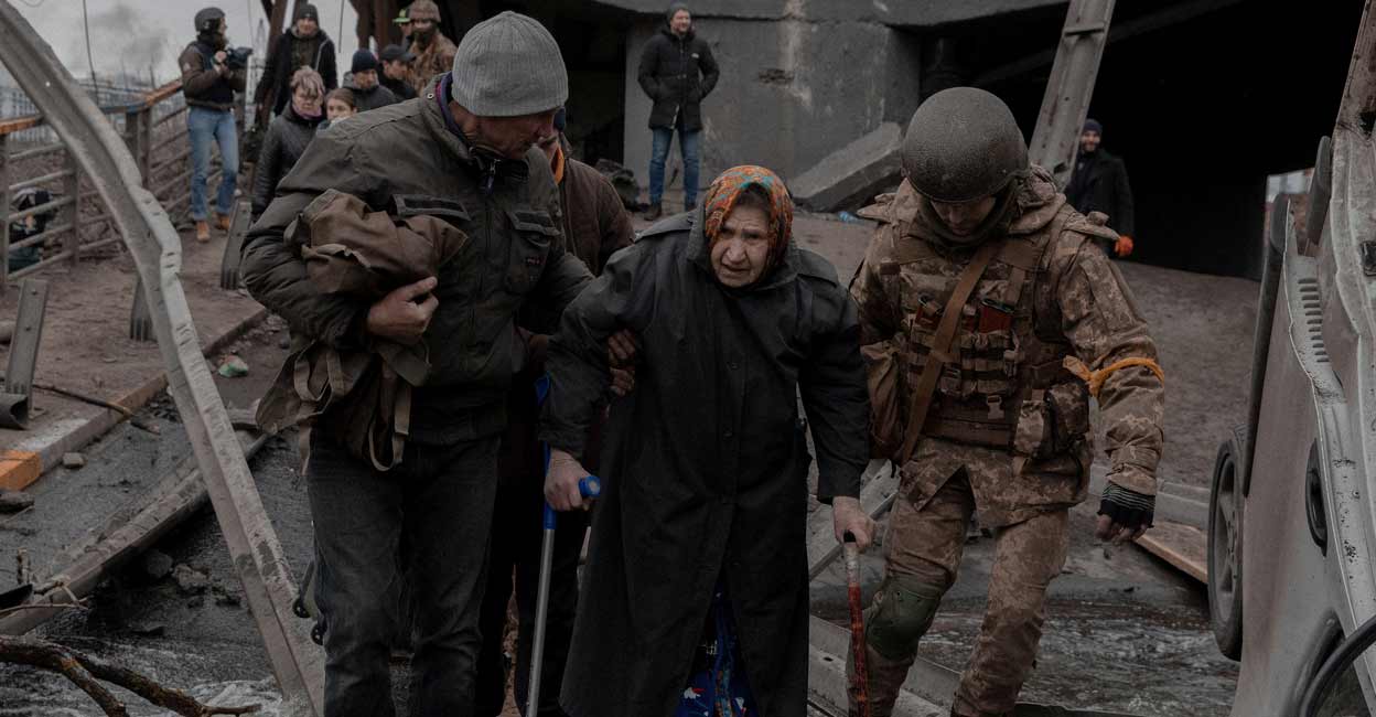 An elderly woman is helped while crossing a destroyed bridge as she tries to leave the city of Irpin, in the Kyiv region, Ukraine March 5, 2022. Photo: Jedrzej Nowicki/Agencja Wyborcza.pl via REUTERS