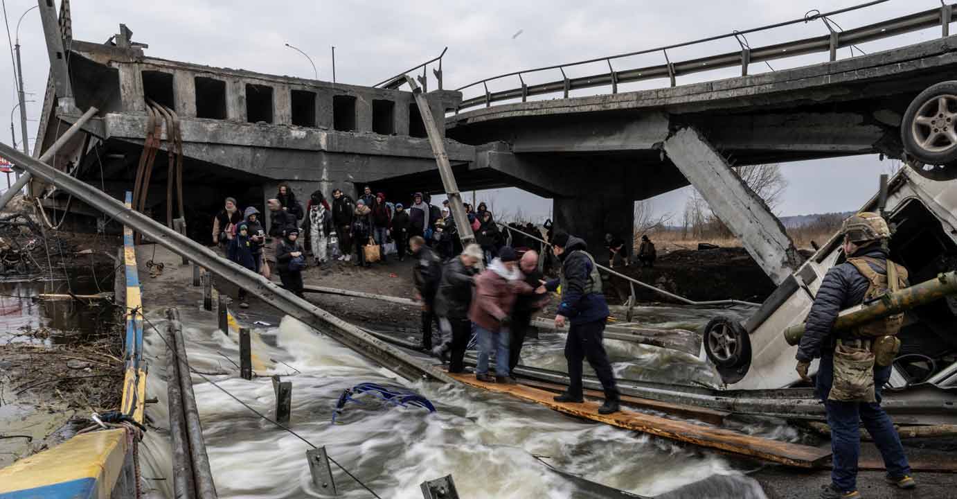 Local residents cross a destroyed bridge as they evacuate from the town of Irpin, after days of heavy shelling on the only escape route used by locals, while Russian troops advance towards the capital, in Irpin, near Kyiv, Ukraine March 7, 2022. Photo: REUTERS/Carlos Barria