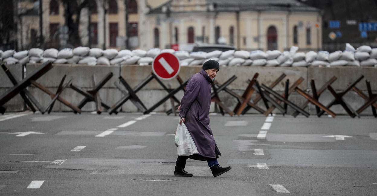 UKRAINE-CRISIS-KYIV-DEFENCE A woman crosses the street as anti-tank constructions are seen in central Kyiv, Ukraine March 7, 2022. Photo: REUTERS/Gleb Garanic