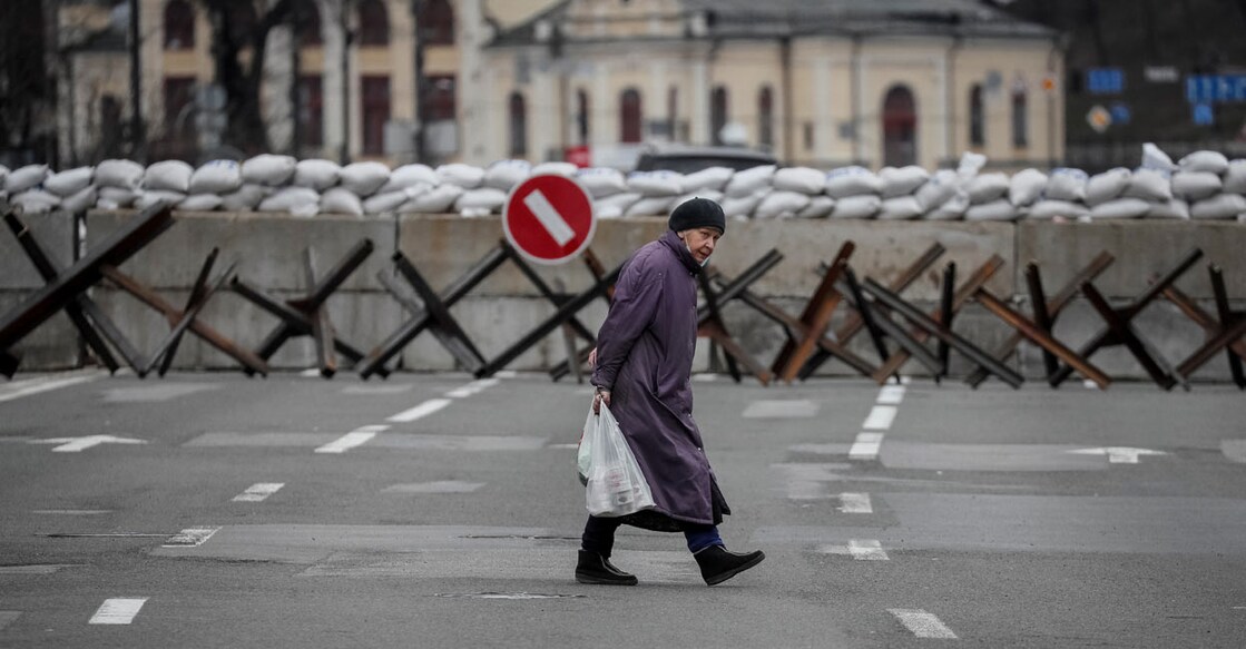 UKRAINE-CRISIS-KYIV-DEFENCE A woman crosses the street as anti-tank constructions are seen in central Kyiv, Ukraine March 7, 2022. Photo: REUTERS/Gleb Garanic
