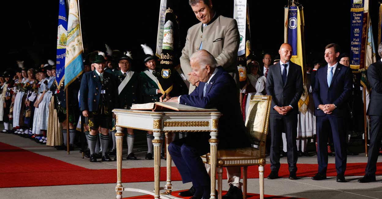 G7 nations ban Russian gold as summit starts under shadow of Ukraine war US President Joe Biden, next to Bavaria's State Premier Markus Soeder, signs the Golden Book of the Bavarian State government as he arrives for a G7 summit at Munich International Airport near Munich, Germany June 25, 2022. Photo: Jonathan Ernst/Reuters