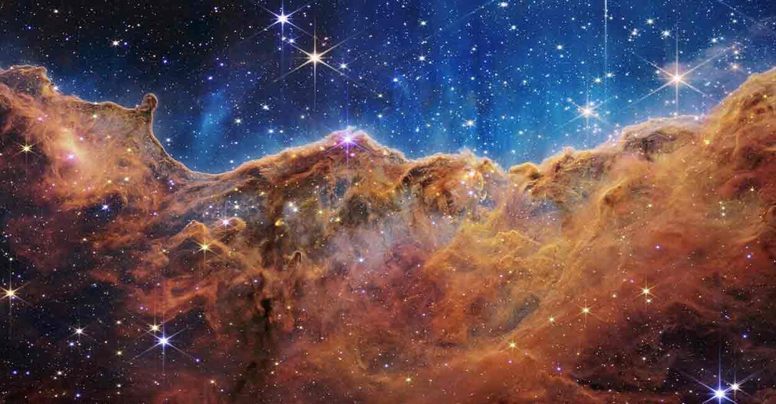 The "Cosmic Cliffs" of the Carina Nebula is seen in an image divided horizontally by an undulating line between a cloudscape forming a nebula along the bottom portion and a comparatively clear upper portion, with data from NASA's James Webb Space Telescope. Speckled across both portions is a starfield, showing innumerable stars of many sizes. Photo: NASA, ESA, CSA, STScI, Webb ERO Production Team/Handout via REUTERS