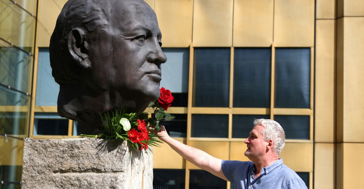 A man places a rose on a sculpture of Mikhail Gorbachev in memory of the final leader of the Soviet Union, at the "Fathers of Unity" memorial in Berlin, Germany August 31, 2022. Photo: REUTERS/Lisi Niesner
