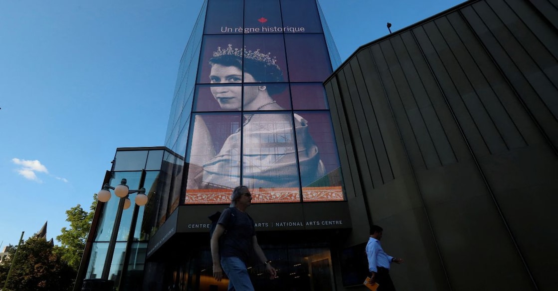 People walk by as a tribute to Queen Elizabeth appears on the National Arts Centre, after Queen Elizabeth's passing, in Ottawa, Ontario, Canada, September 8, 2022. PHOTO: Reuters/Patrick Doyle