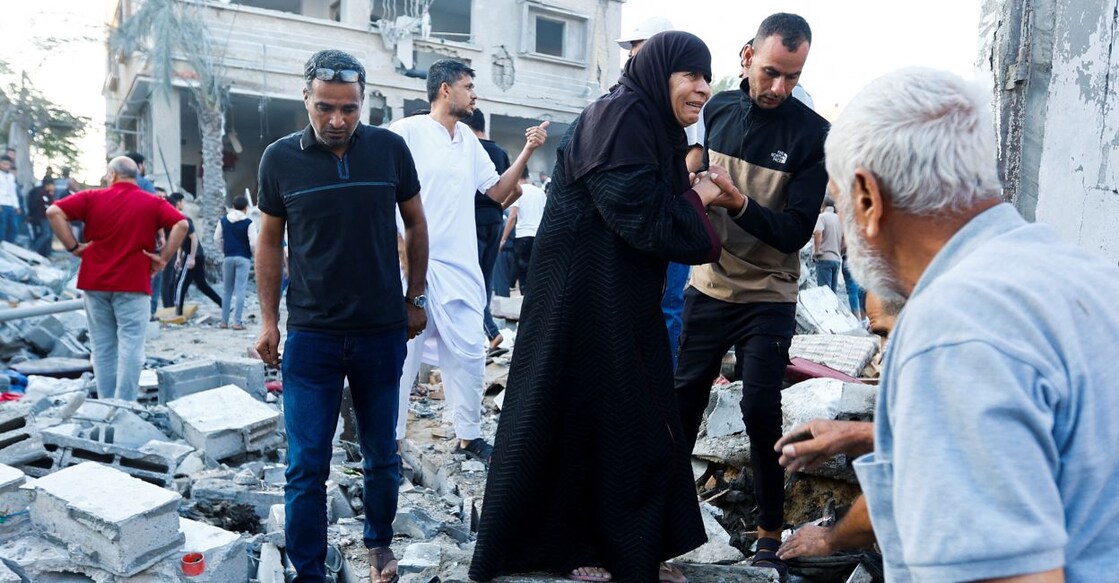 People walk on rubble in the aftermath of a strike amid the conflict with Israel in Khan Younis, in the southern Gaza Strip, October 12, 2023. Photo: Reuters/Ibraheem Abu Mustafa